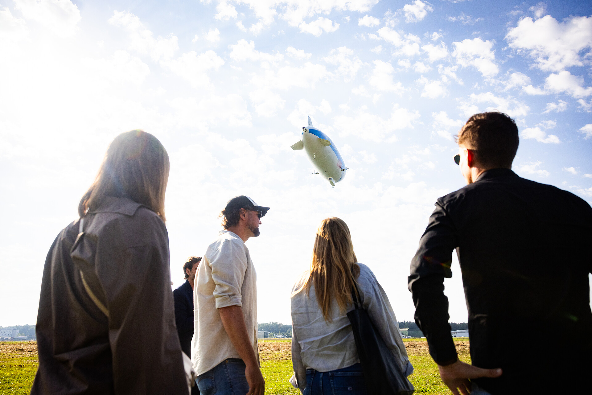 Zeppelin fliegt davon und Gäste schauen ihm nach